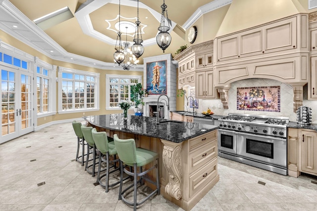 kitchen featuring a kitchen breakfast bar, backsplash, an island with sink, dark stone counters, and double oven range