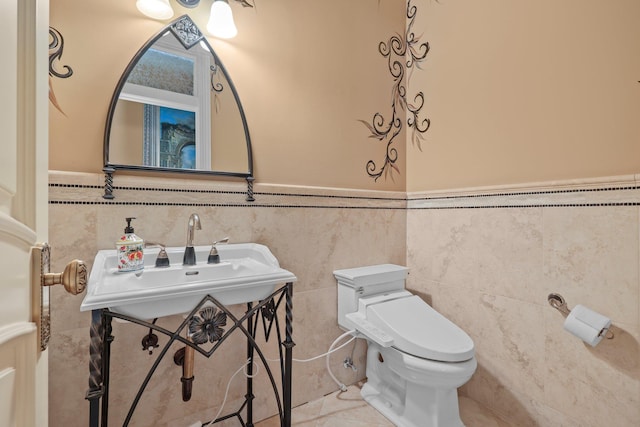 bathroom with tile patterned floors, sink, toilet, and tile walls