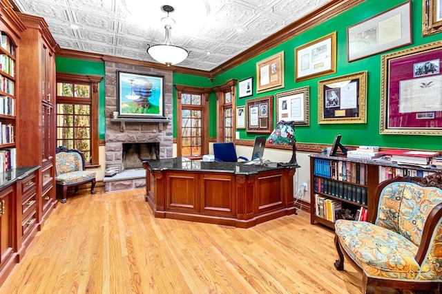 home office with a stone fireplace, light hardwood / wood-style flooring, and ornamental molding