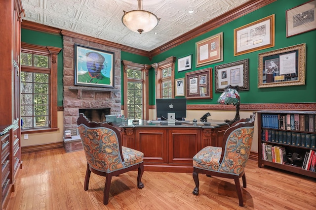 office area featuring light hardwood / wood-style flooring, crown molding, and a stone fireplace