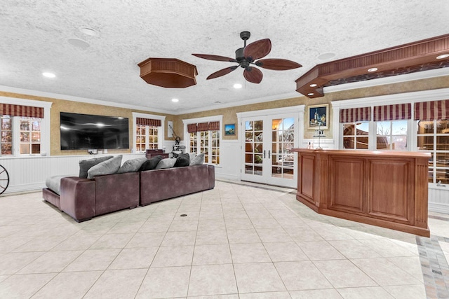 tiled living room featuring french doors, a textured ceiling, ceiling fan, and ornamental molding