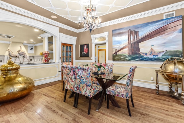 dining space featuring an inviting chandelier, crown molding, and light hardwood / wood-style flooring