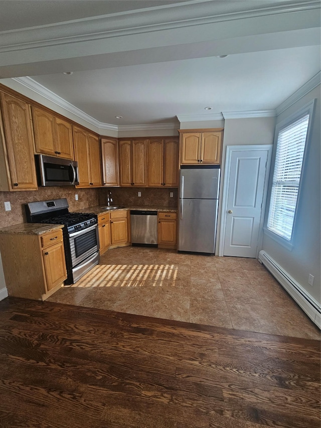 kitchen with dark tile patterned flooring, ornamental molding, backsplash, and appliances with stainless steel finishes