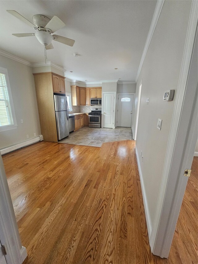 kitchen with a baseboard heating unit, crown molding, ceiling fan, light wood-type flooring, and appliances with stainless steel finishes