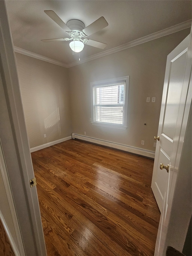 empty room featuring ceiling fan, dark hardwood / wood-style flooring, ornamental molding, and a baseboard heating unit