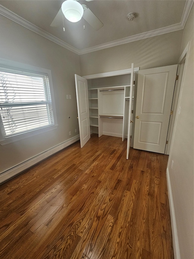 unfurnished bedroom with baseboard heating, ceiling fan, crown molding, wood-type flooring, and a closet