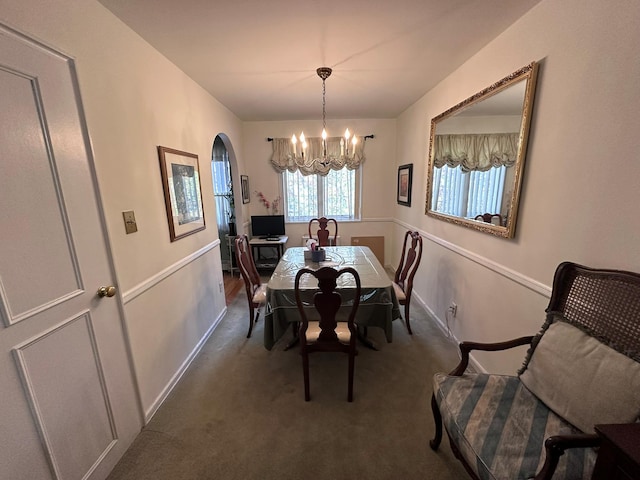 dining area featuring dark colored carpet and a notable chandelier