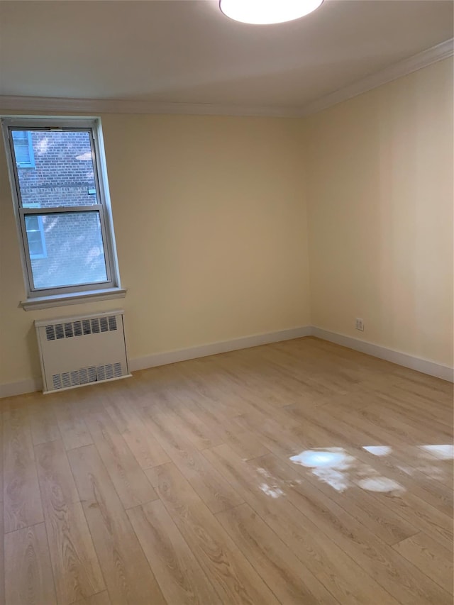 empty room with radiator, ornamental molding, and light wood-type flooring