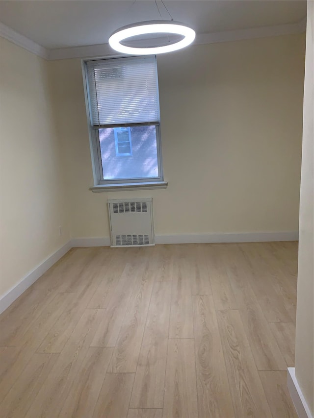 spare room featuring light hardwood / wood-style floors, ornamental molding, and radiator