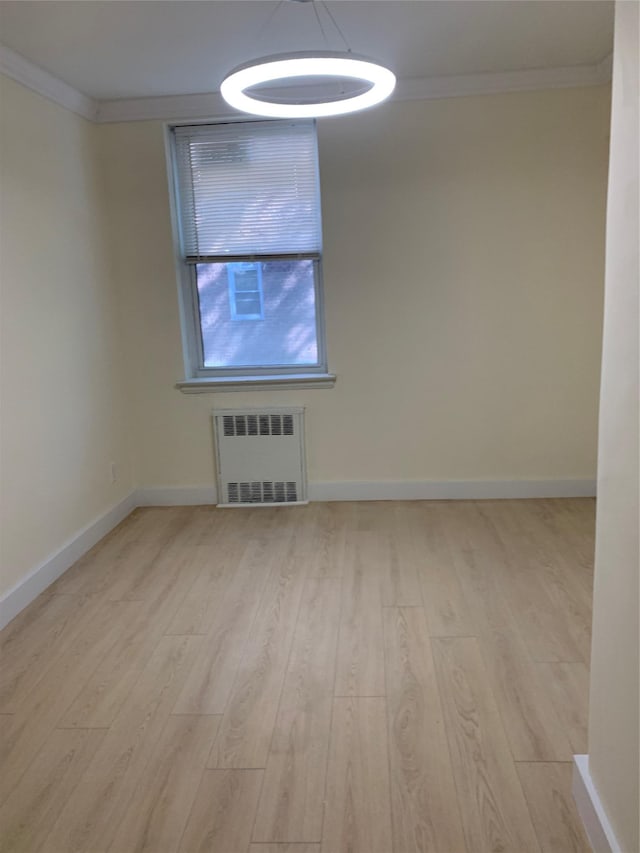 unfurnished room featuring radiator heating unit, ornamental molding, and light wood-type flooring