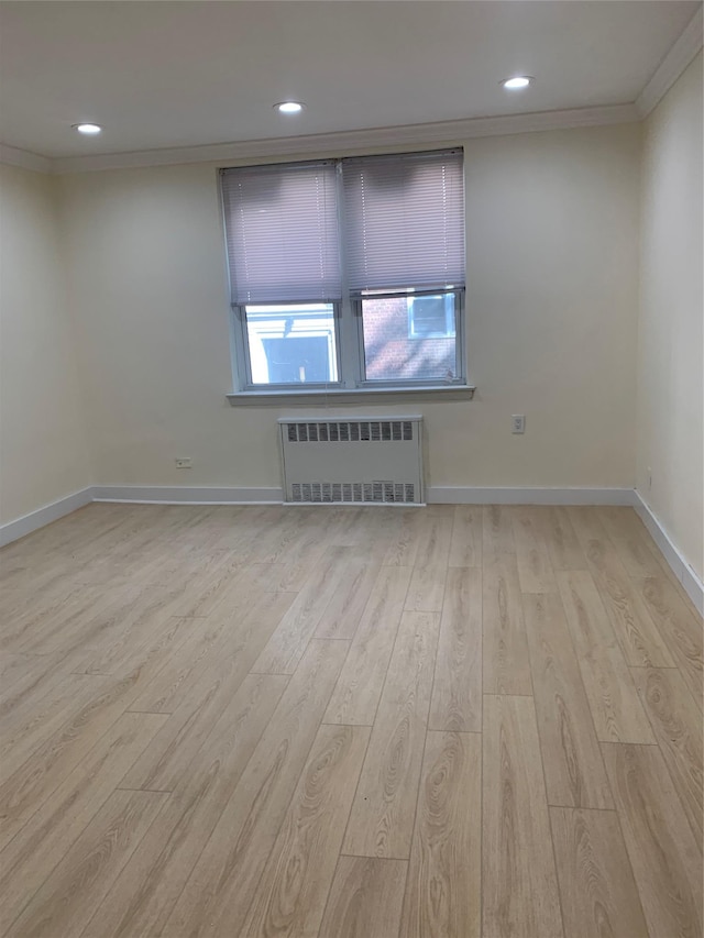 empty room with radiator heating unit, light wood-type flooring, and ornamental molding