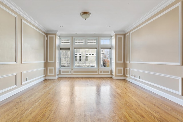 spare room featuring crown molding, plenty of natural light, and light hardwood / wood-style floors