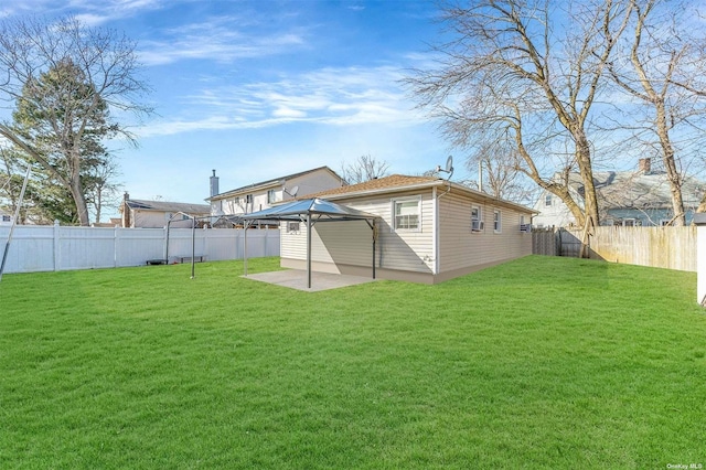 rear view of property featuring a gazebo, a yard, and a patio