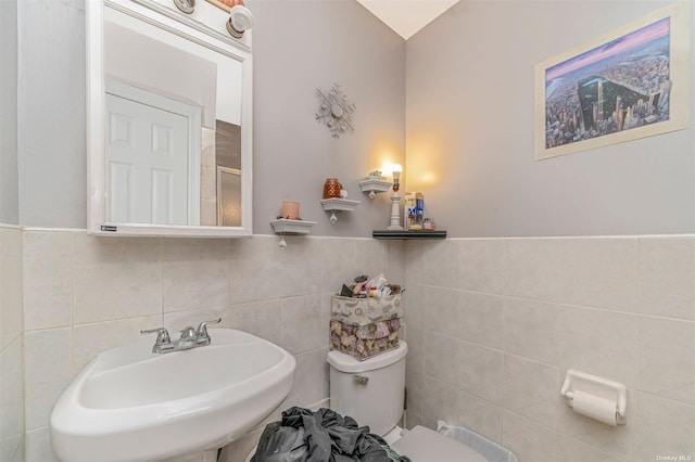 bathroom featuring sink, tile walls, and toilet