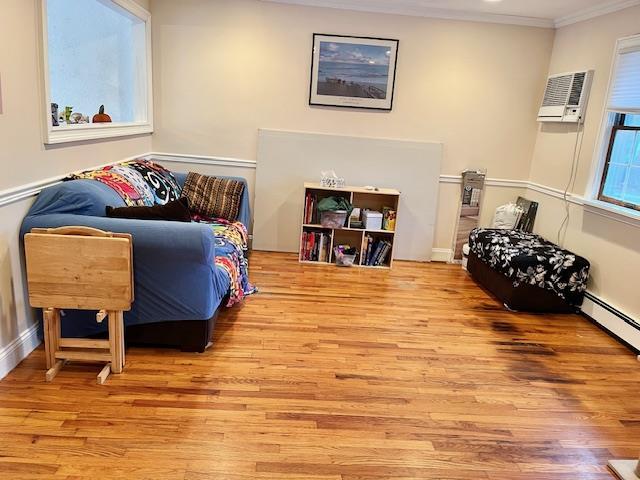 sitting room featuring crown molding, a wall mounted air conditioner, and hardwood / wood-style flooring