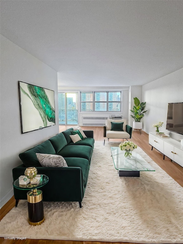 living room featuring radiator heating unit, a textured ceiling, and wood-type flooring