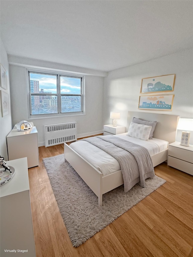 bedroom with radiator heating unit and hardwood / wood-style flooring