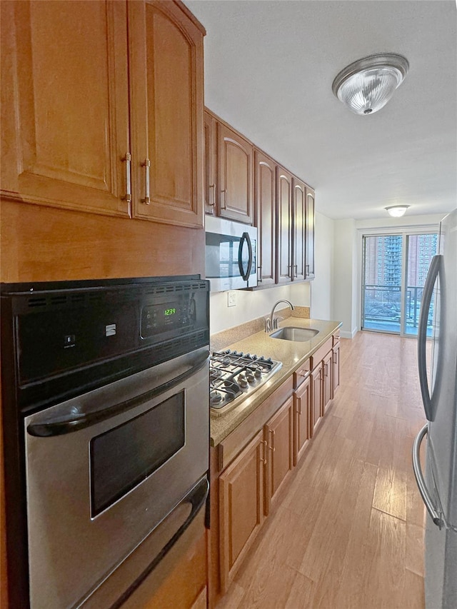 kitchen with sink, stainless steel appliances, and light wood-type flooring