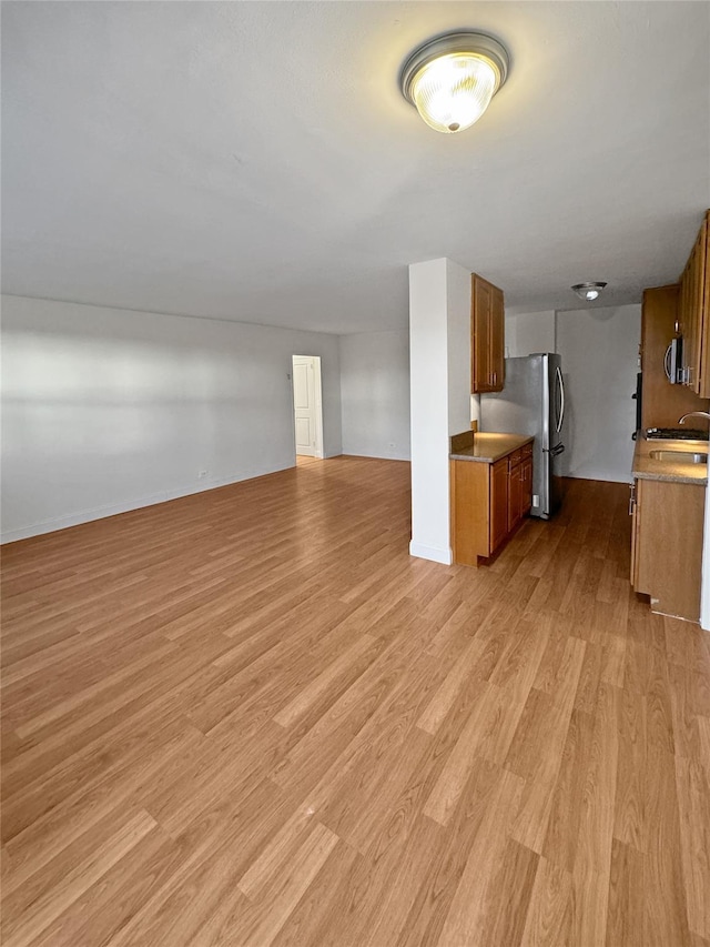 unfurnished living room featuring light hardwood / wood-style flooring and sink