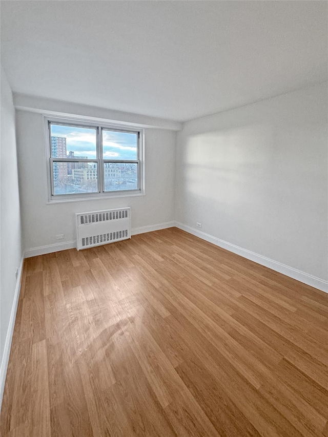 spare room featuring light wood-type flooring and radiator heating unit