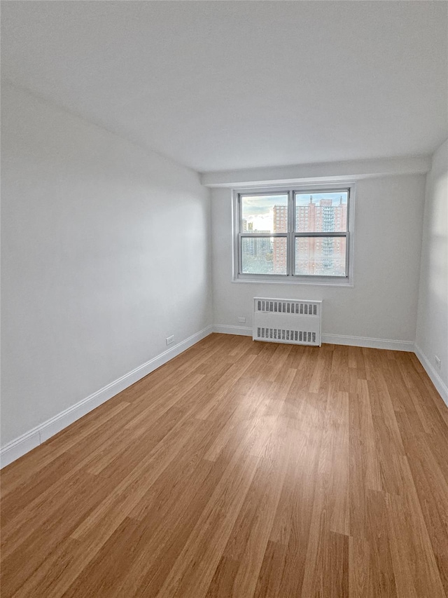 unfurnished room featuring light wood-type flooring and radiator