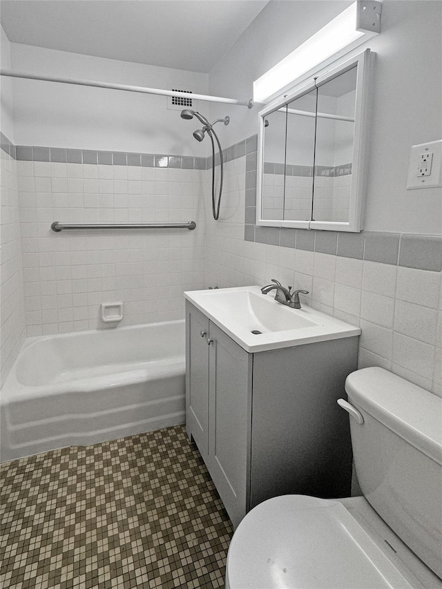 full bathroom with toilet, vanity, tiled shower / bath combo, and tile walls