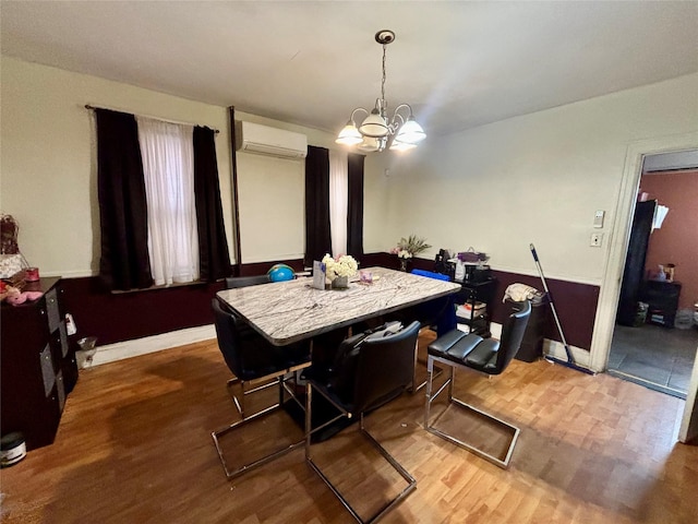 dining area with a wall mounted air conditioner, light hardwood / wood-style flooring, and a notable chandelier