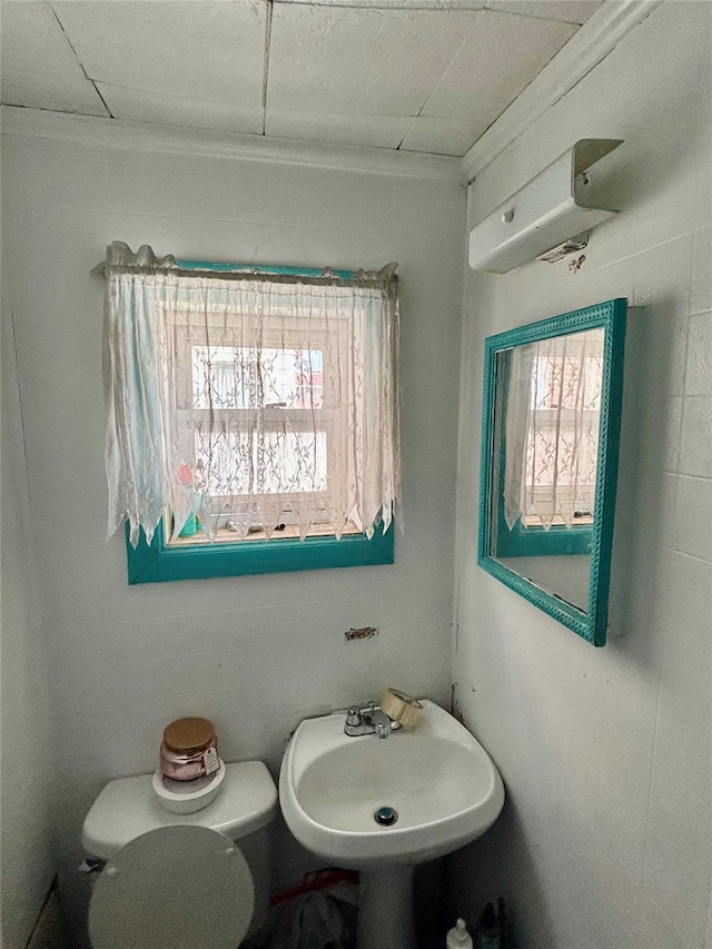 bathroom featuring sink, plenty of natural light, a wall mounted air conditioner, and toilet