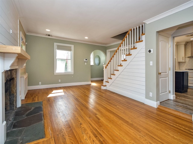 unfurnished living room featuring hardwood / wood-style floors, ornamental molding, and a fireplace