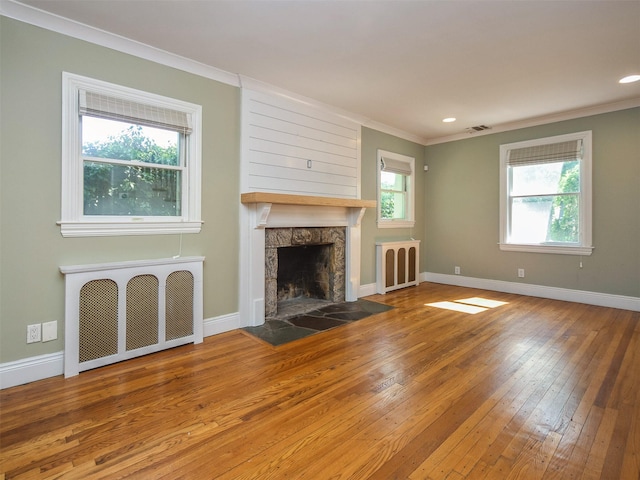 unfurnished living room featuring radiator heating unit, plenty of natural light, and wood-type flooring