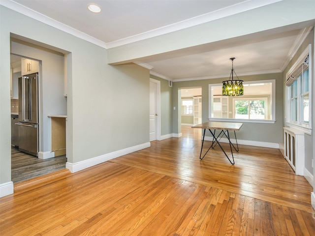 unfurnished dining area with a notable chandelier, light hardwood / wood-style floors, and crown molding