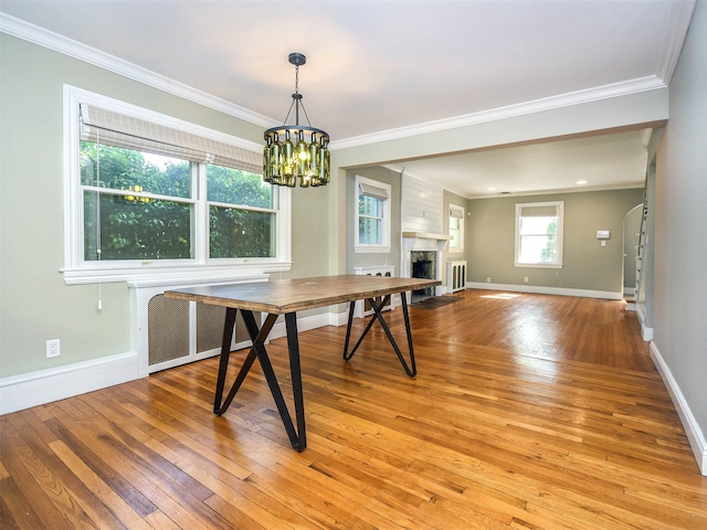 dining room with radiator, crown molding, a large fireplace, and light wood-type flooring