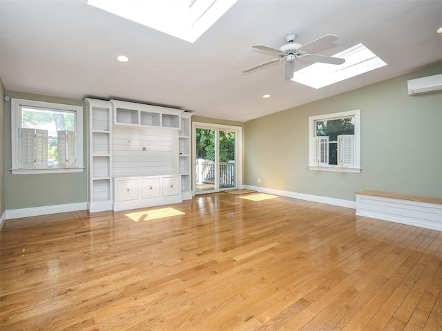 unfurnished living room featuring lofted ceiling with skylight, a healthy amount of sunlight, and light hardwood / wood-style floors