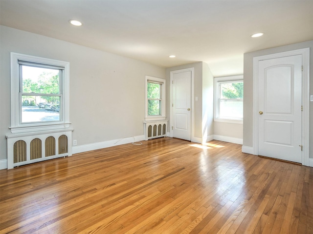 empty room featuring radiator, light hardwood / wood-style flooring, and plenty of natural light