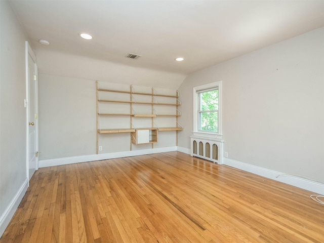 interior space with radiator heating unit, hardwood / wood-style flooring, and vaulted ceiling