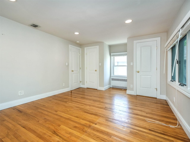 unfurnished room with radiator heating unit and light hardwood / wood-style flooring