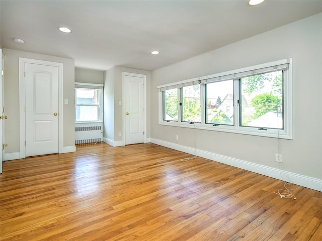 spare room featuring radiator, a healthy amount of sunlight, and light hardwood / wood-style floors