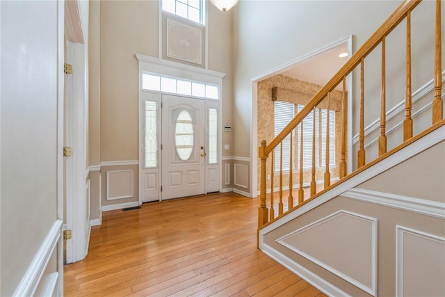 foyer entrance with light hardwood / wood-style floors and a towering ceiling