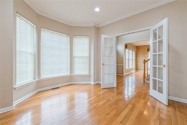 unfurnished room featuring french doors, light wood-type flooring, and ornamental molding