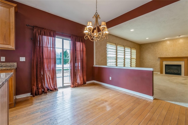 unfurnished dining area with light hardwood / wood-style floors and an inviting chandelier