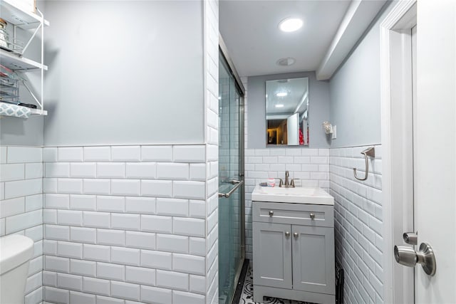 bathroom featuring a tile shower, vanity, tile walls, and toilet