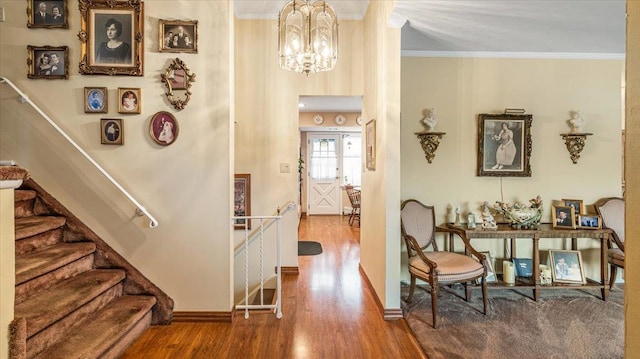 entryway with hardwood / wood-style floors, ornamental molding, and an inviting chandelier