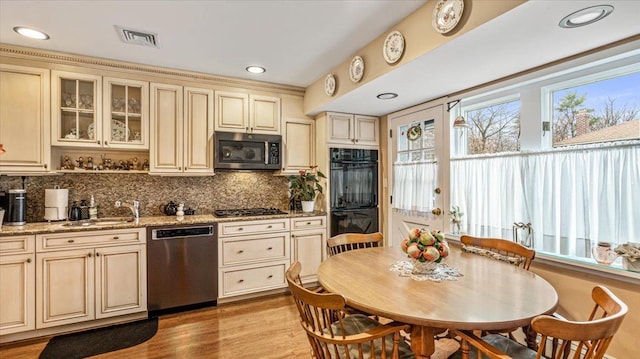 kitchen featuring light wood-type flooring, light stone counters, stainless steel appliances, sink, and cream cabinets