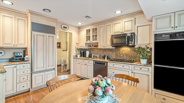 kitchen with light hardwood / wood-style floors, light stone counters, appliances with stainless steel finishes, and cream cabinets