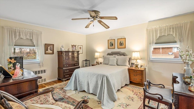 bedroom featuring light wood-type flooring, radiator, and ceiling fan