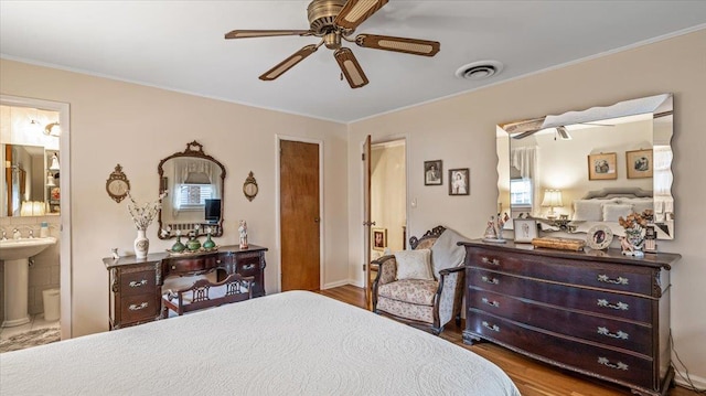 bedroom with ceiling fan, crown molding, sink, wood-type flooring, and connected bathroom