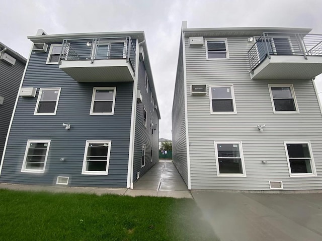 back of house featuring a balcony and a wall unit AC