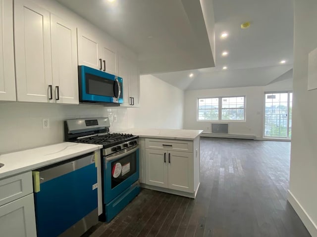 kitchen with appliances with stainless steel finishes, dark hardwood / wood-style floors, white cabinetry, and lofted ceiling