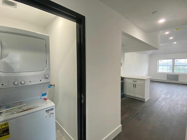 laundry room featuring stacked washer and dryer, a baseboard radiator, and dark hardwood / wood-style floors