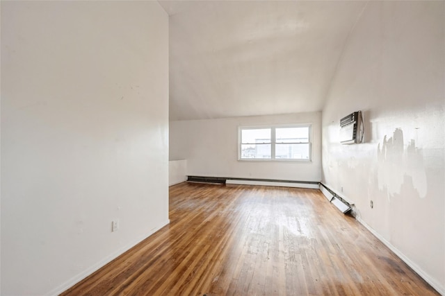 additional living space with hardwood / wood-style floors, vaulted ceiling, and a wall mounted AC